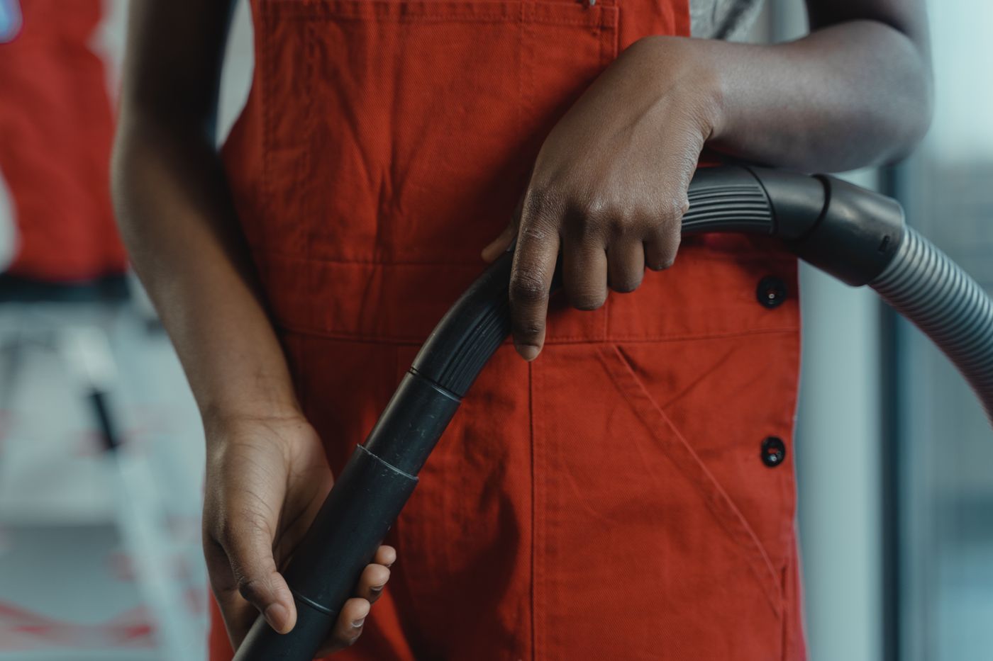 Person holding the curved handle and hose of a vacuum cleaner.